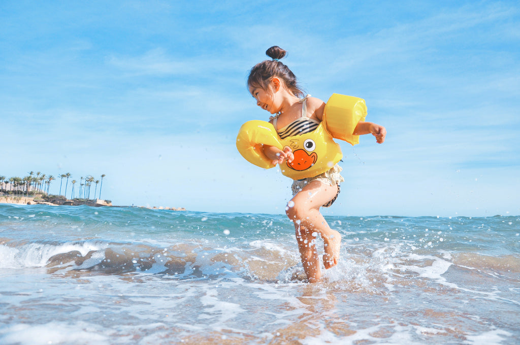toddler in floaties plays at the beach