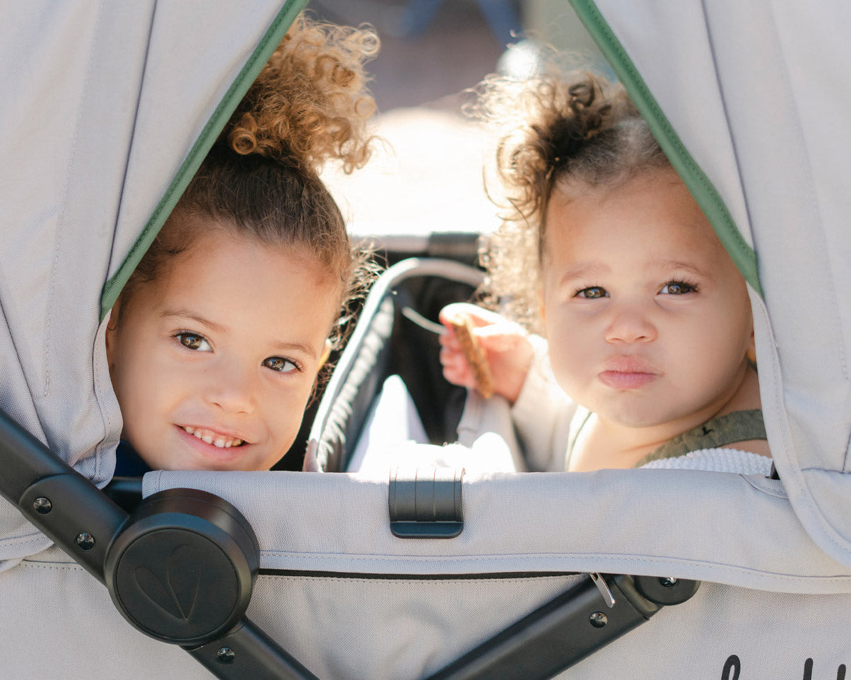 Two kids peek out from under the caravan coupe sun canopies