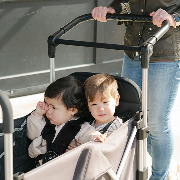 two kids sit side by side in the caravan double seat kit stroller wagon
