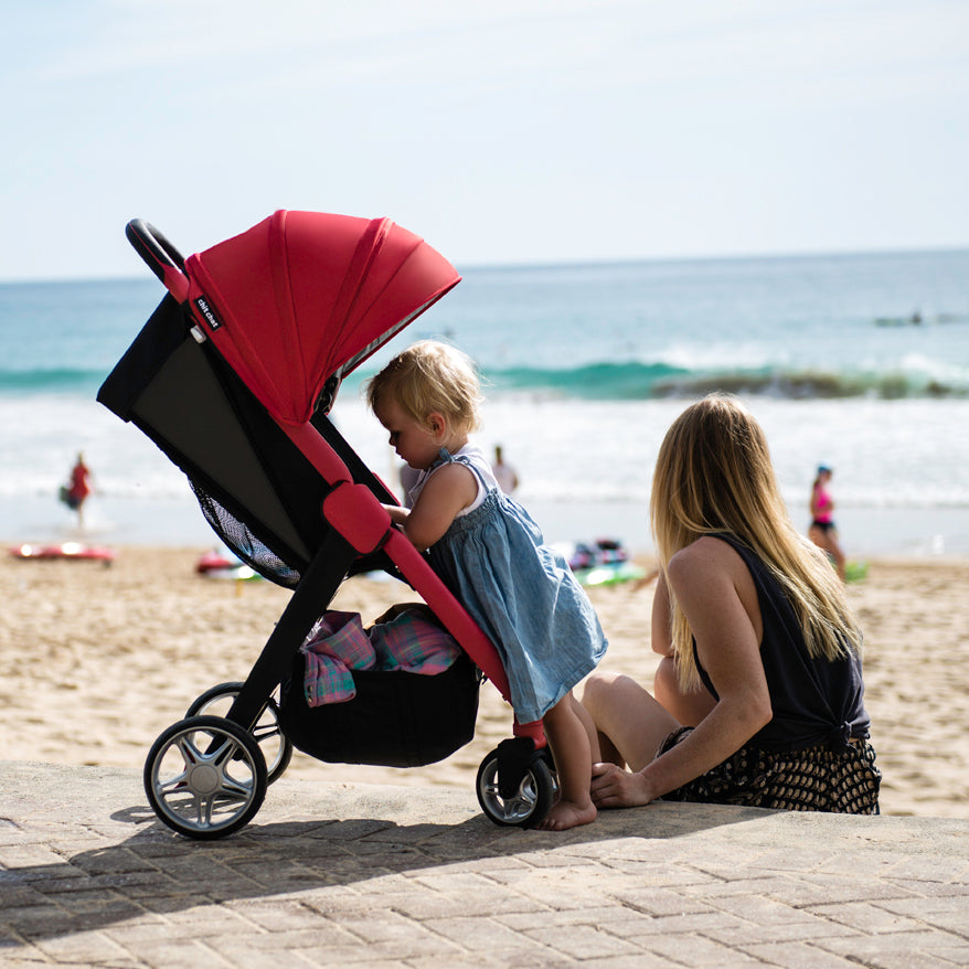 red chit chat stroller by the beach with mom and baby