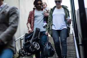 Light and easy to carry stroller. Easy to fold stroller. great for travel and public transportation. Chit Chat stroller. Image: Larktale family carries the folded chit chat stroller down a flight of stairs with one hand