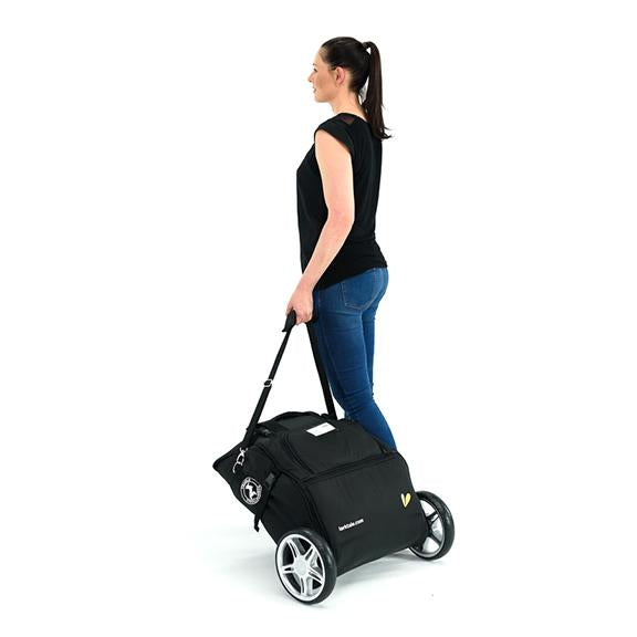 woman pulls coast stroller in travel bag behind her like luggage